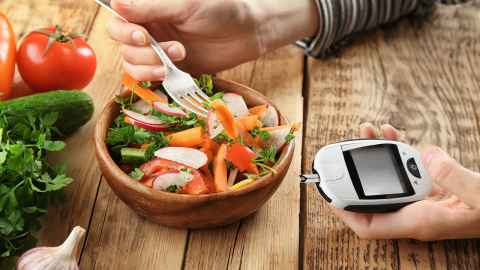 Person eating a salad with glucose monitor