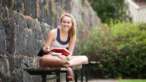 Woman sitting on seat outside studying