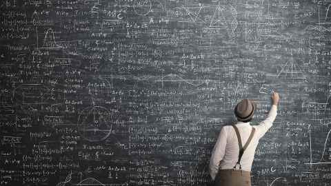Teacher drawing on blackboard filled with equations