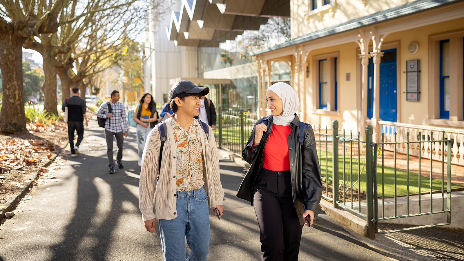 International students walking down leafy street.