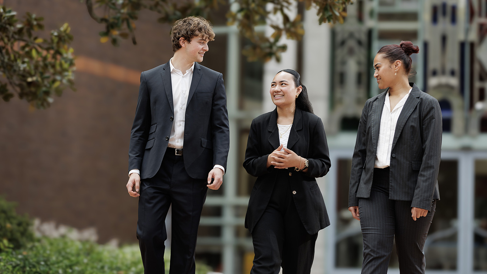 Three students walking together outside the high court.