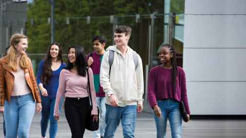 Group of happy students walking together outside.