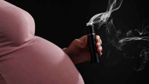 A pregnant person holiding a vape.