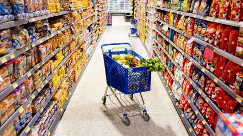 Trolley full of fruit and vegetables in a supermarket aisle