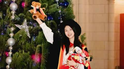 Grace Wei holds a graduation bear in front of a decorated Christmas tree