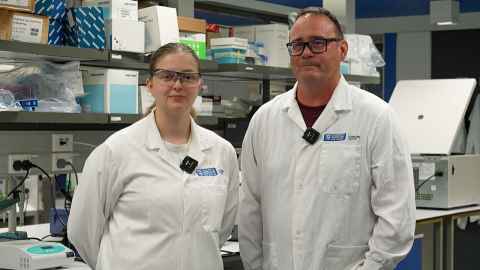 Joelle Ireland and Justin O'Sullivan wearing white coats in a lab