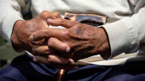 Hands of an older person holding a walking stick