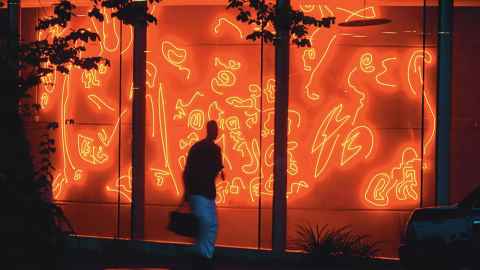 Light sculpture at night with a blurry person standing in front
