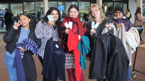 Five students with armfuls of clothing from the Winter Clothes Drive.