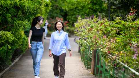 Two students walking in a garden setting.