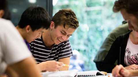 Students around a table reading.