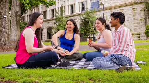 Four smiling students plating cards outside