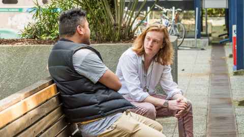 Two men sitting on a bench talking