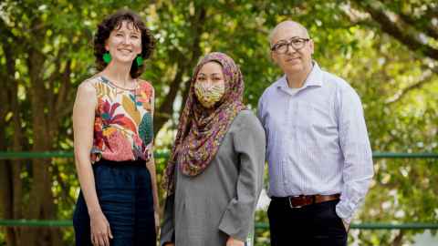 Three members of the DEI team smiling at the camera while posing for a group photo.