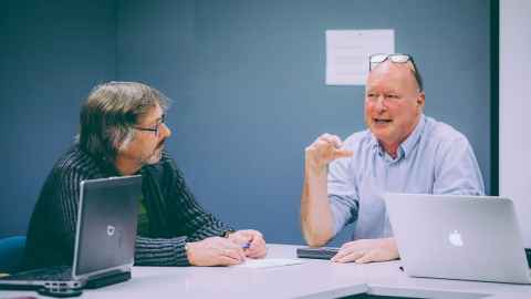 Two mature age staff talking