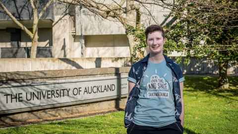 Dr Ruth Monk next to a University of Auckland sign