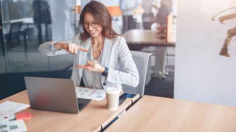 A woman in a workplace using sign language in a video call
