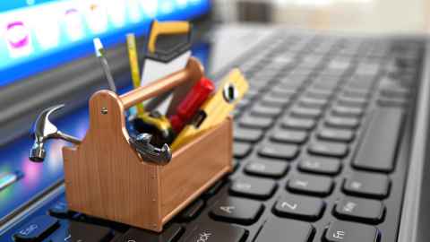 Laptop keyboard with a miniature tradespersons' toolkit sitting on it.