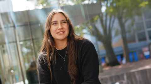 Female student sitting outside looking off to the side.