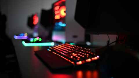 A keyboard illuminated in red with other peripherals lit up in the background
