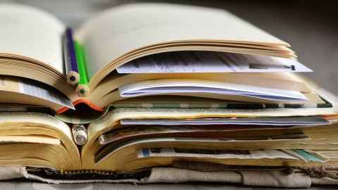 Stack of books, papers and pencils