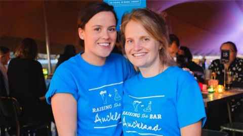 Two women wearing blue "Raising the Bar" t-shirts
