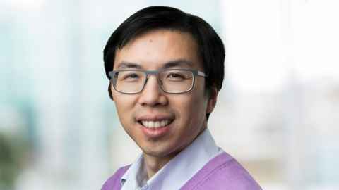 A young man with glasses, smiling.