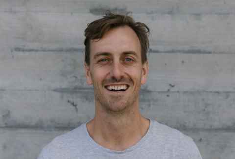 A man in a grey t-shirt, smiling.