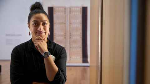 A young woman in an art gallery, with artworks in the background.