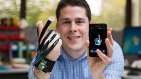 A young man holding a phone with a device attached to his other hand.