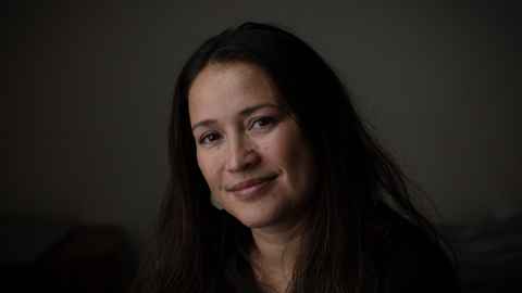 A woman with long, dark hair, smiling.