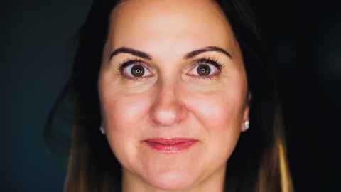 A dark-haired woman looking intently at the camera.