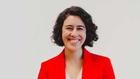 A smiling, dark-haired woman in a red jacket.