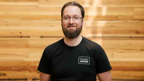 A man with a beard, wearing a t-shirt that says 'thought wired'.
