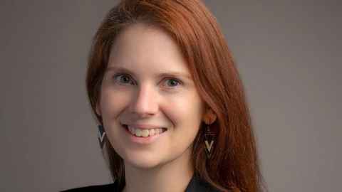 A smiling young woman with long red hair.