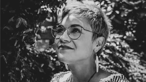 A black-and-white photo of a woman with short hair, glasses and dangly earrings.