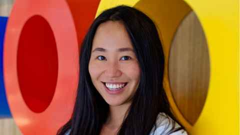 A smiling young woman standing in front of brightly-coloured letters.