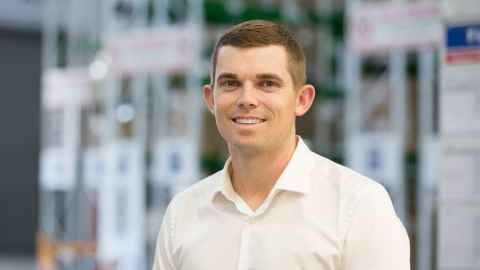 A young man with light brown hair wearing a white shirt.