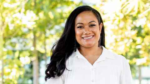 A woman with long, dark hair, wearing a white blouse.