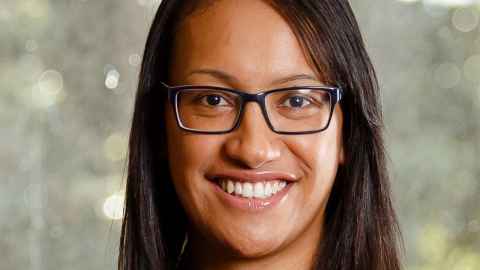 A smiling young woman wearing glasses.