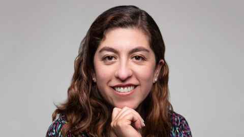 A woman with curly brown hair, smiling.