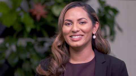 A woman with brown hair, wearing silver earrings and a black jacket.