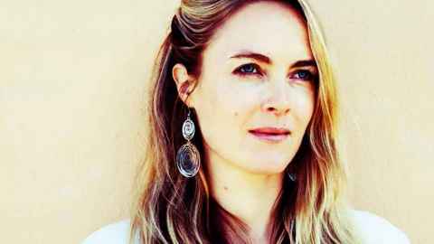 A fair-haired woman with large earrings, looking into the distance.