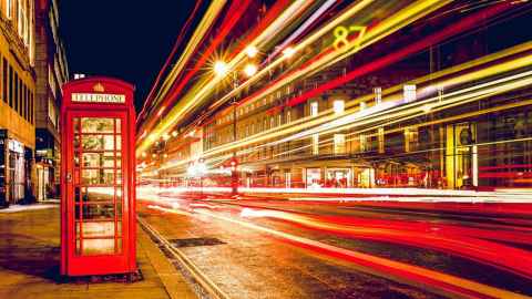 A street at night with a red telephone box.