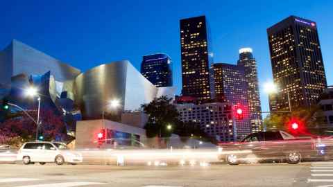 A city street at night with tall, modern buildings.