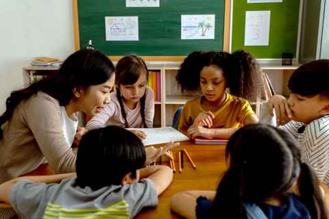A woman and children sitting around a table in a classroom.