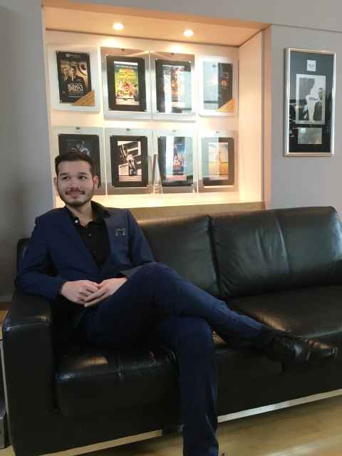 Joshua Ling dressed up in a nice suit sitting on the couch of Paramount Pictures