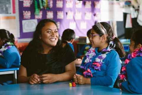 A woman and a little girl sitting at a table in a classroom.