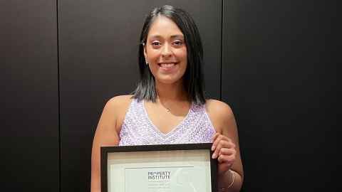 Photo of a young woman in a lavender evening dress, holding a framed certificate.