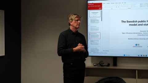 A man standing to the side of a large presentation screen